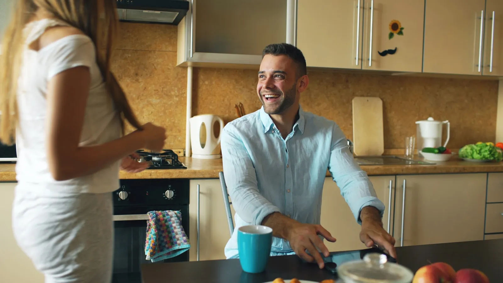 Man en vrouw praten lachend met elkaar in de keuken.