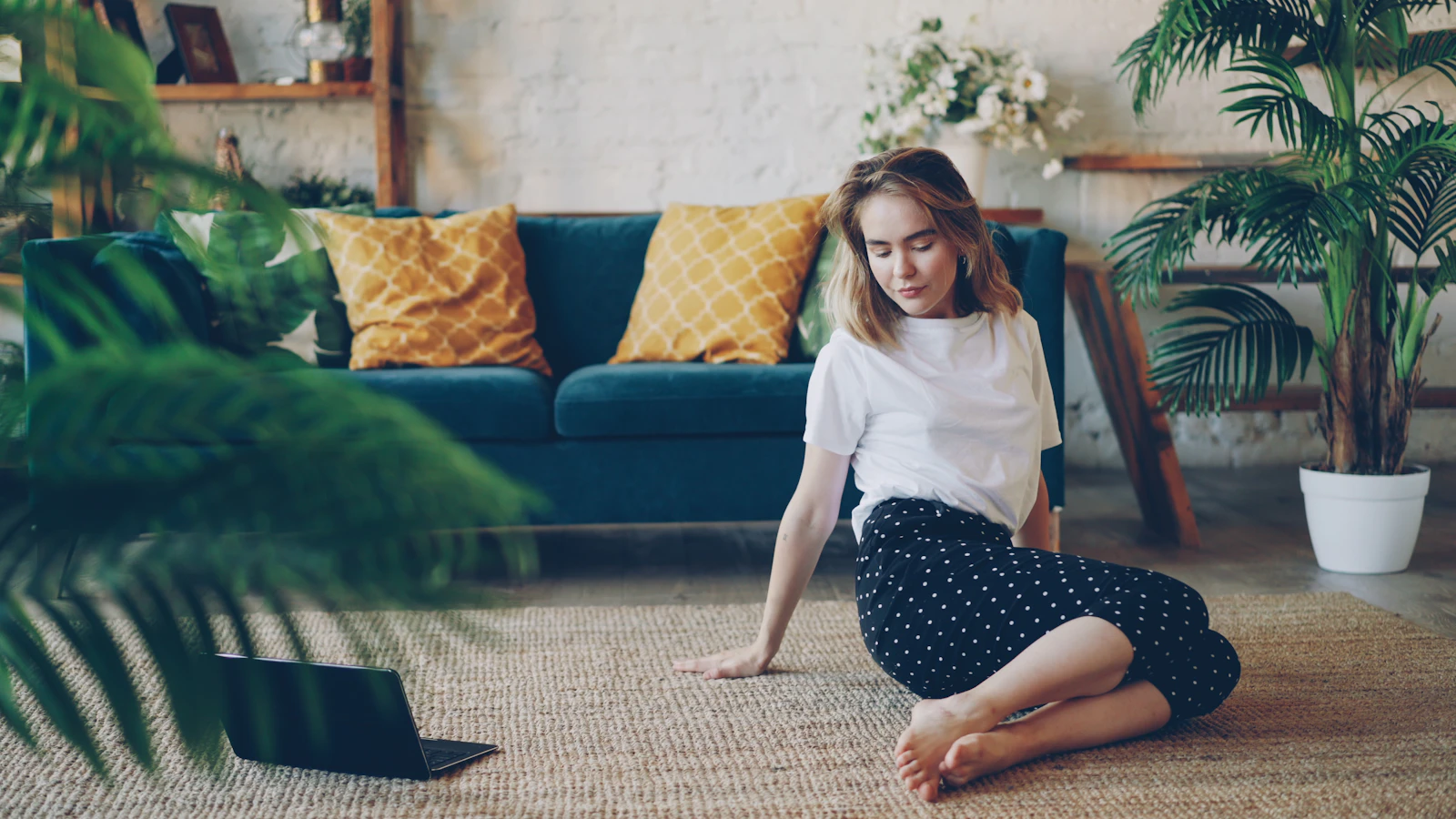 Vrouw zit ontspannen op de vloer in een lichte woonkamer.