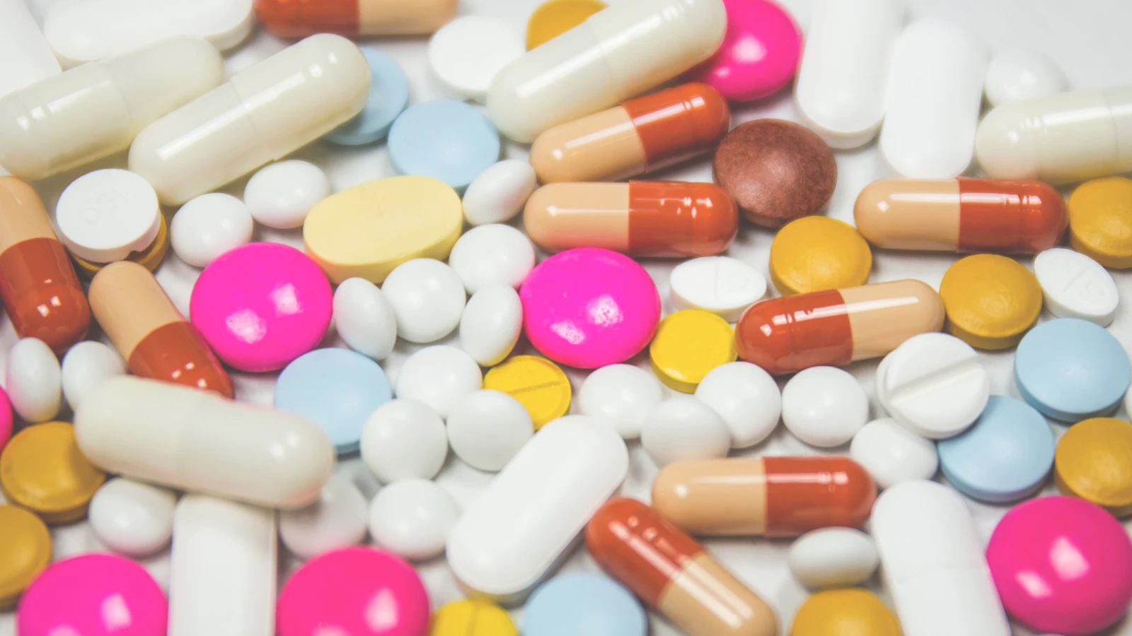 Various tablets and capsules on a light surface.