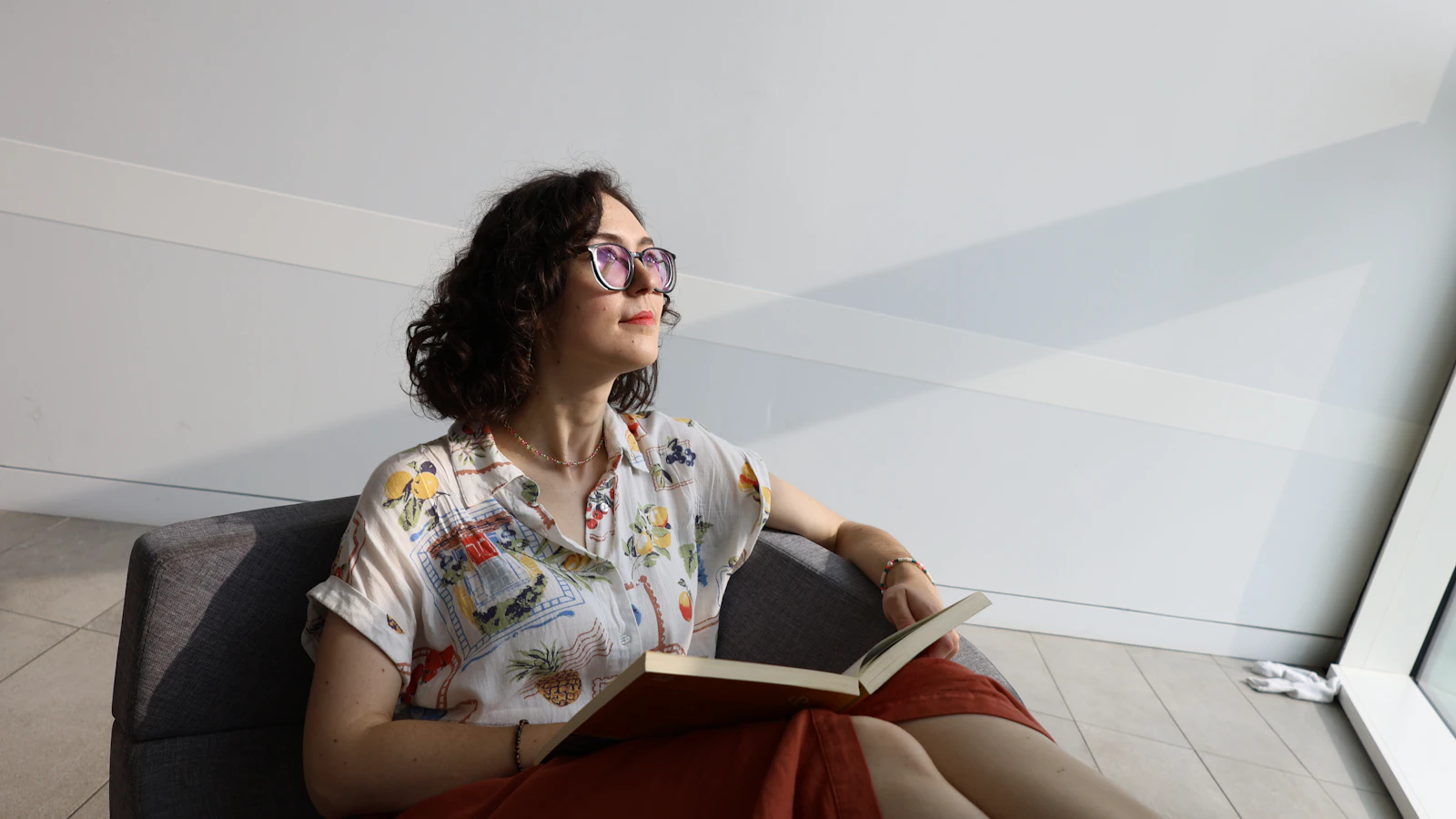 Vrouw zit ontspannen op de bank te lezen in het daglicht.
