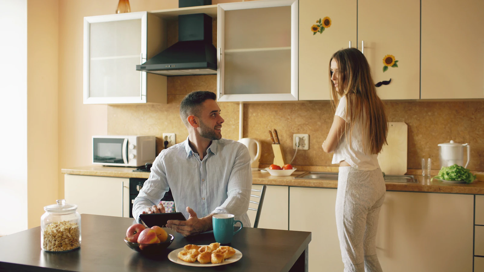 A couple talking calmly together in the kitchen.