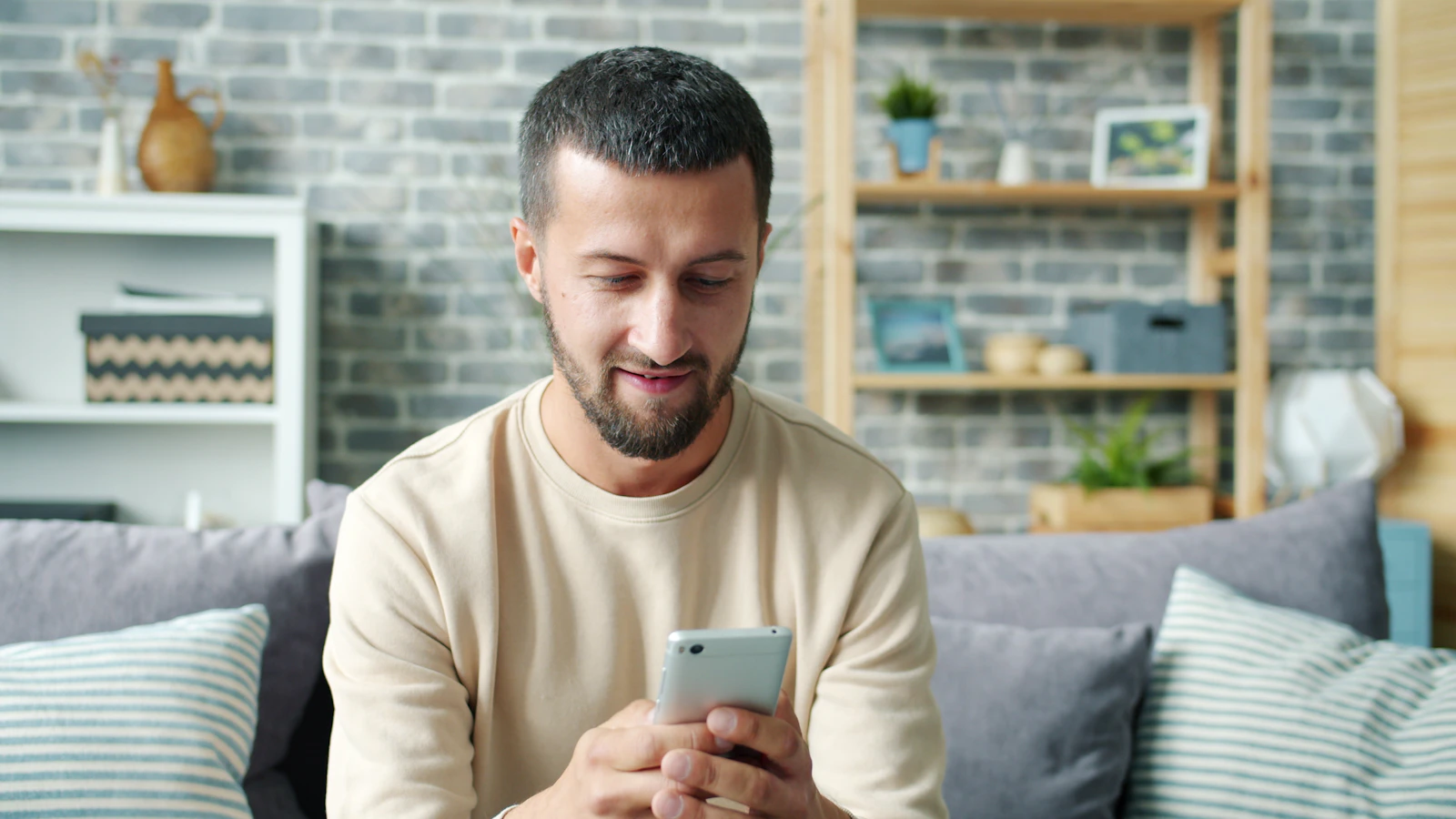A man sitting relaxed on the sofa with his smartphone.