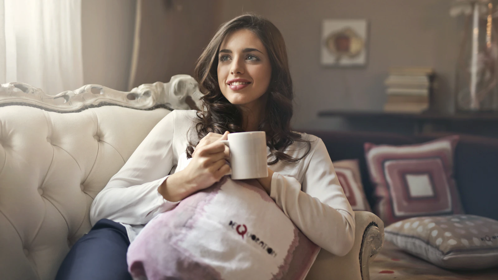 A woman sitting relaxed on the sofa holding a mug in her hands.