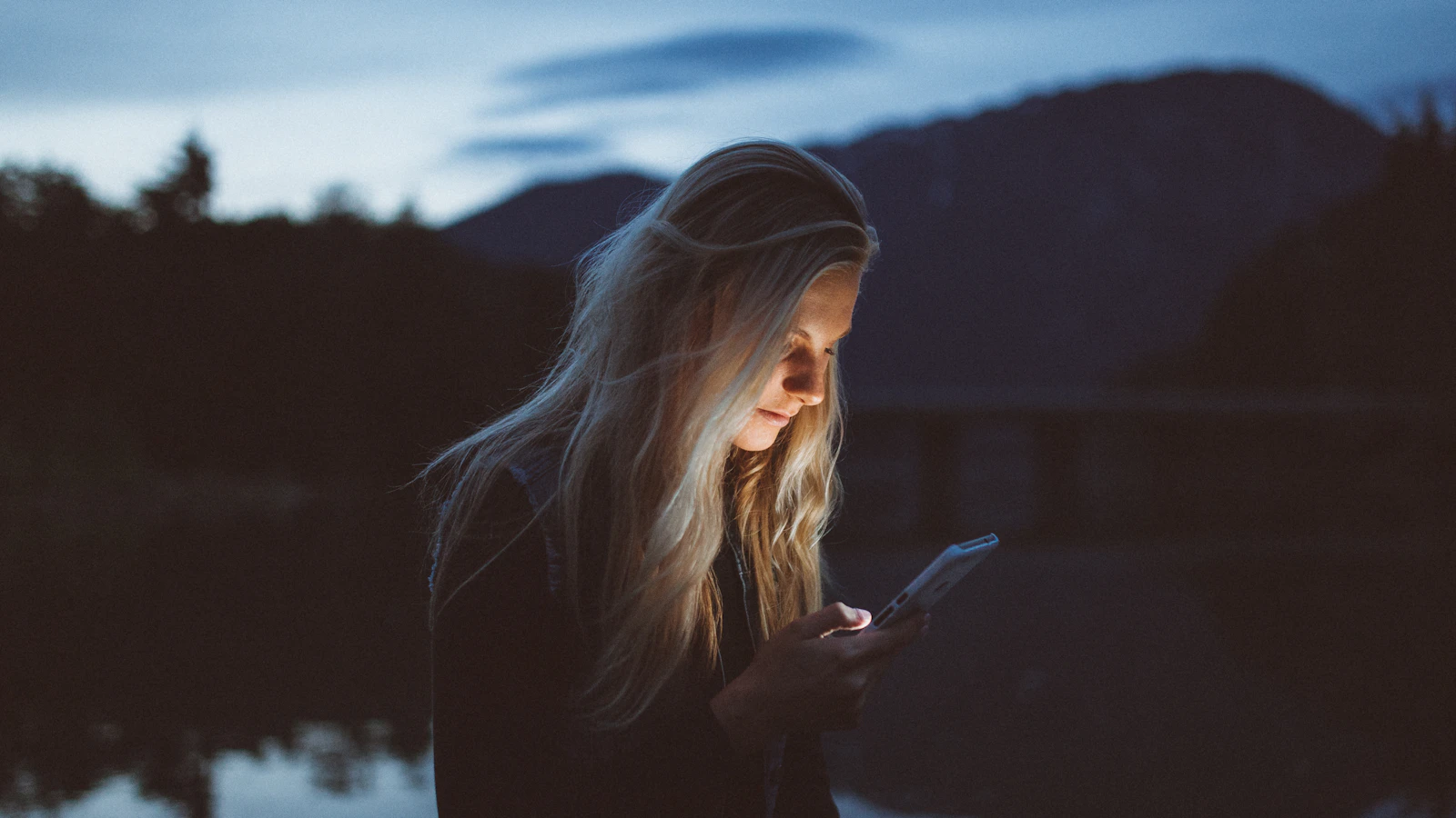 Someone calmly looking at a phone in daylight.
