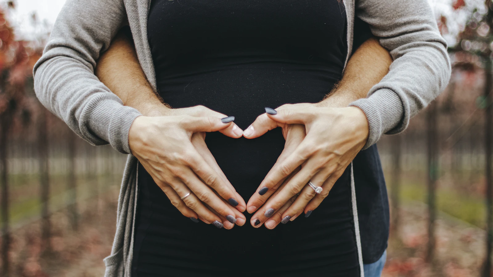 A pregnant woman calmly touching her belly.