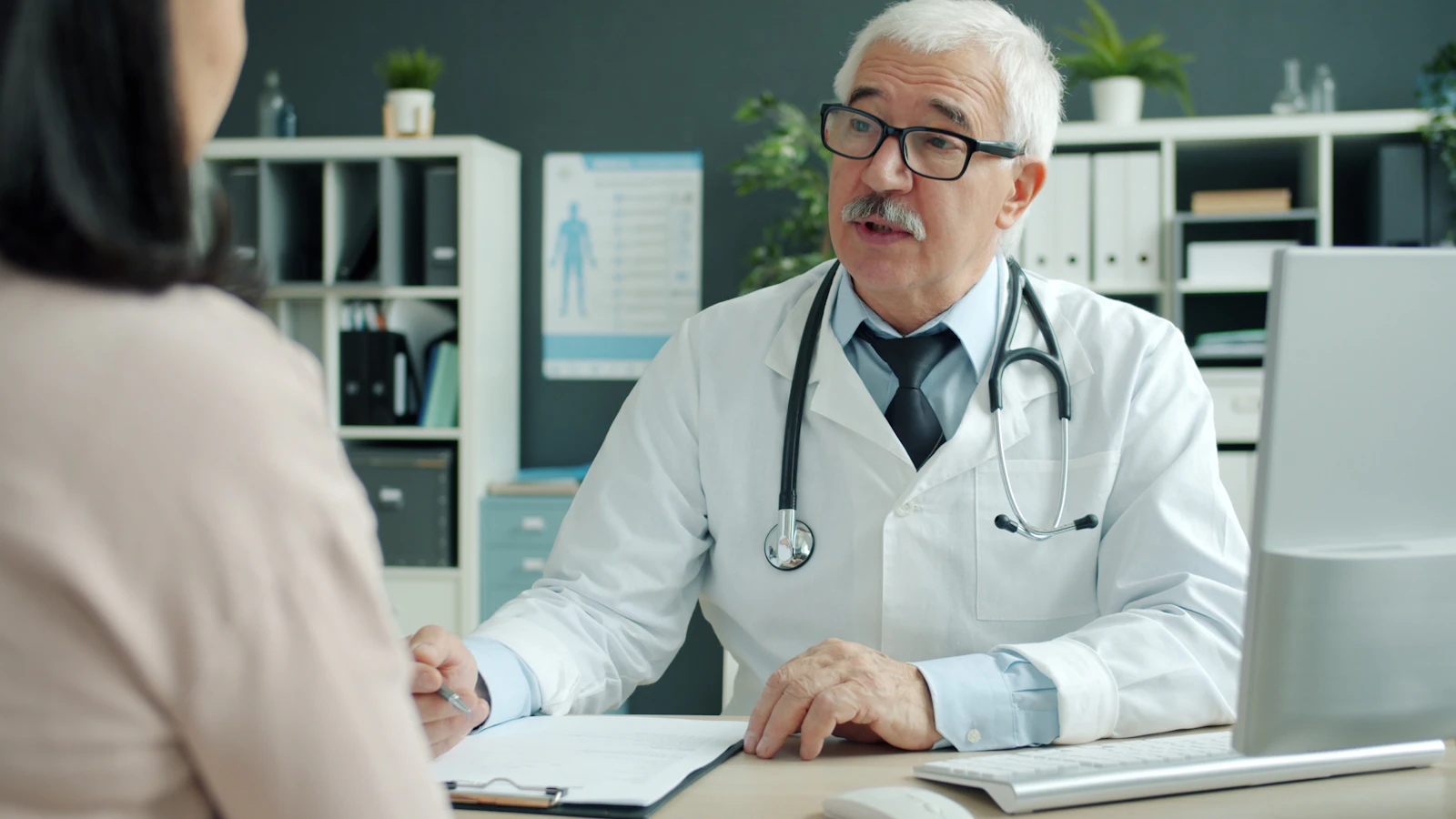 Arts in gesprek met een patient in een spreekkamer over mogelijke klachten.