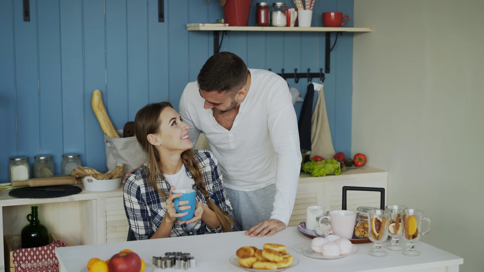Twee mensen praten ontspannen met elkaar aan de keukentafel in de ochtend.