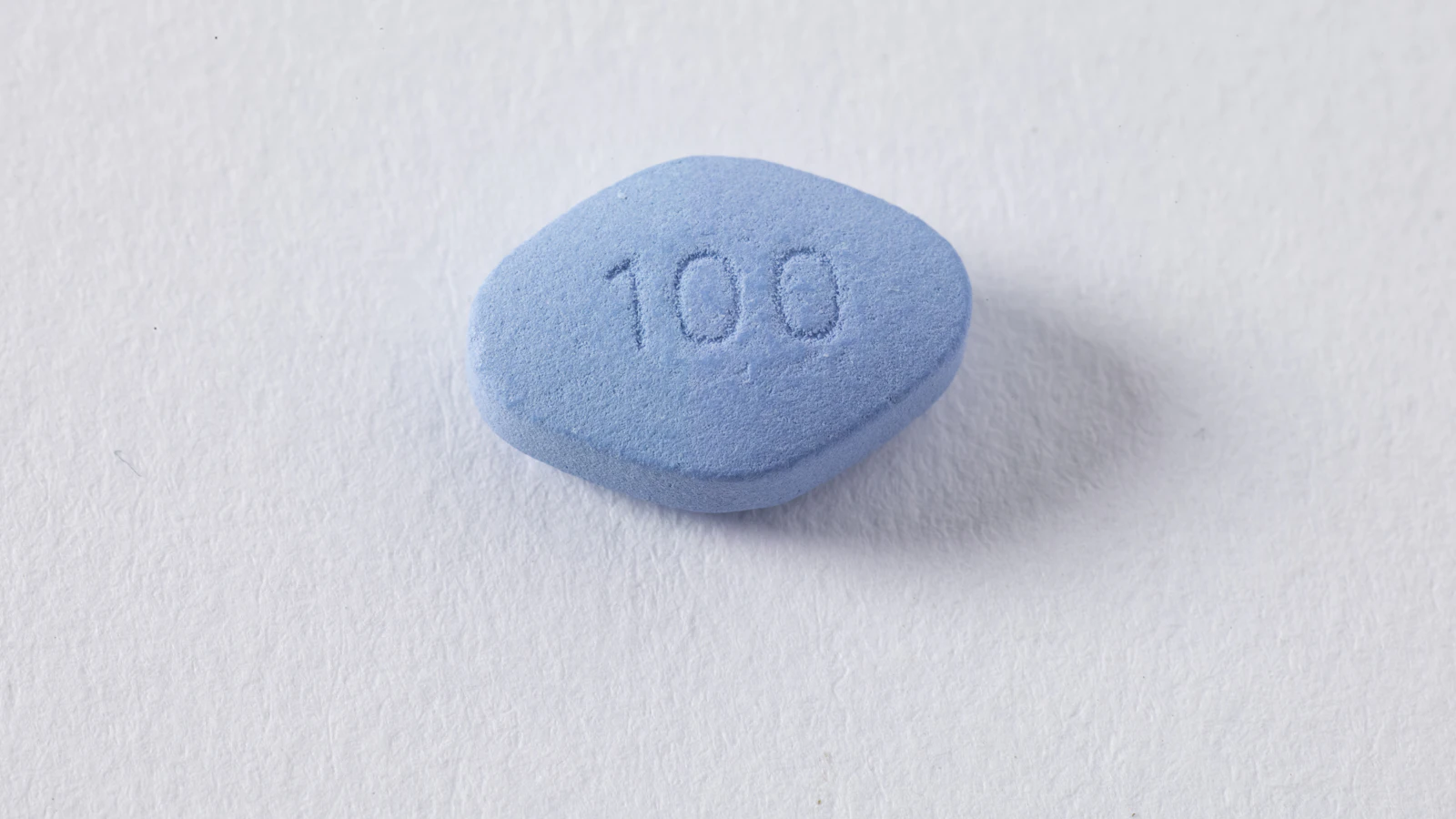 Een enkele medicijnpil op een effen ondergrond.